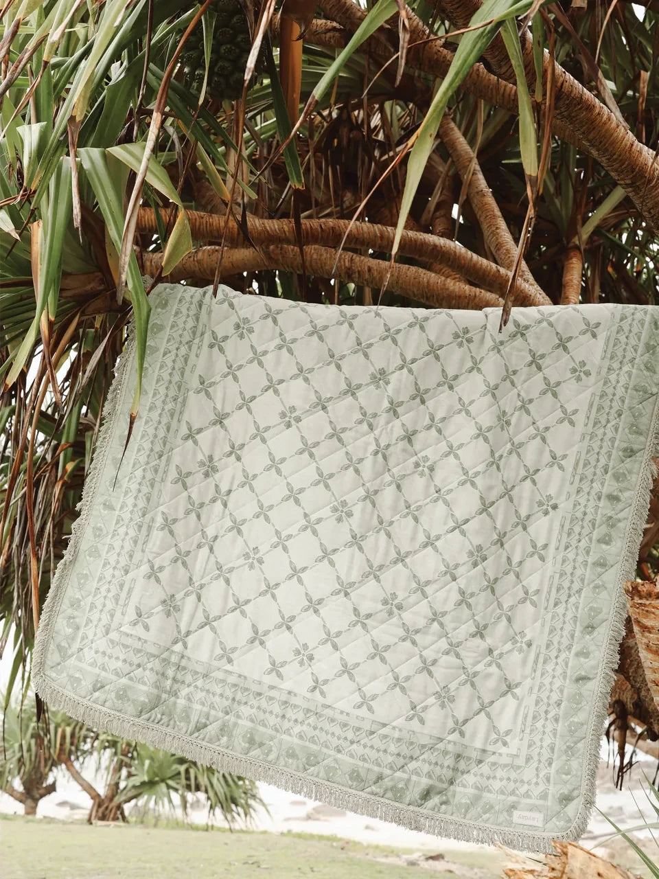 Textured green Laydy Zepher blanket draped over a tree branch with a natural background