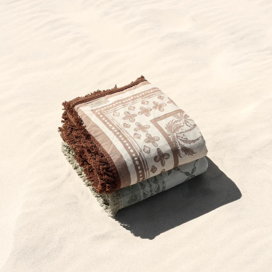 Folded Layday blanket with brown and beige design on a sandy background