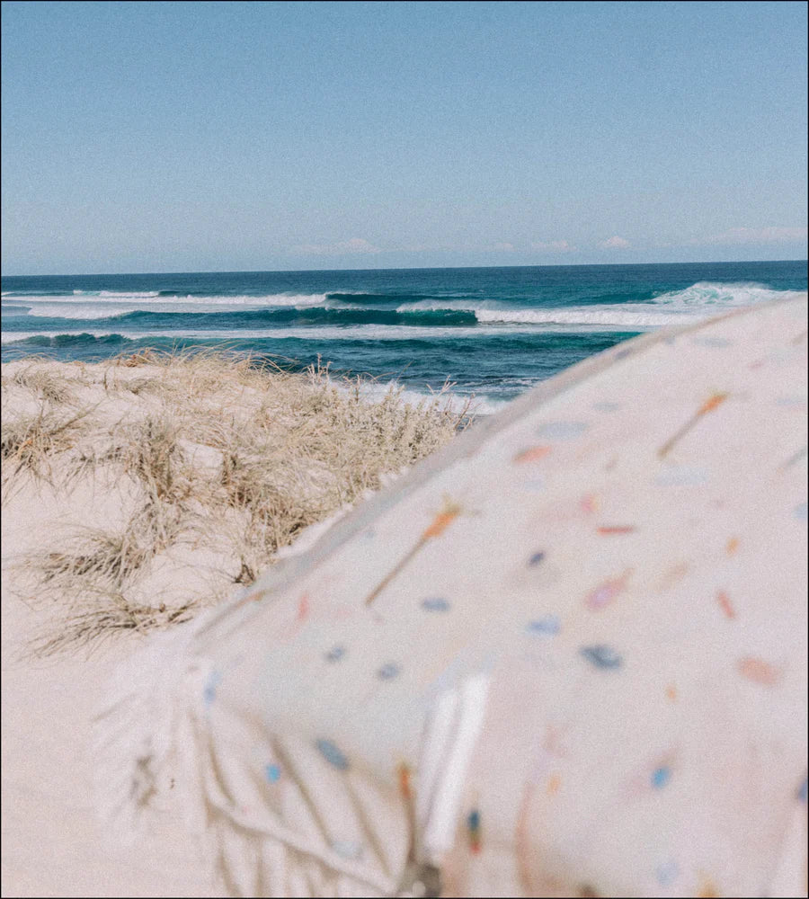 Beach scene with ocean waves and a colorful Layday umbrella.